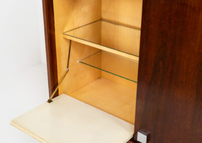 Belgian modernist bar cabinet in rosewood, 1960s. It features a minimalistic design with sleek lines and chrome details. It contains two big and two small sliding doors with lots of storage space on the inside. There are clearly traces of use and age like scratches and some color differences, but overall in good condition. We have a matching sideboard in stock aswell.