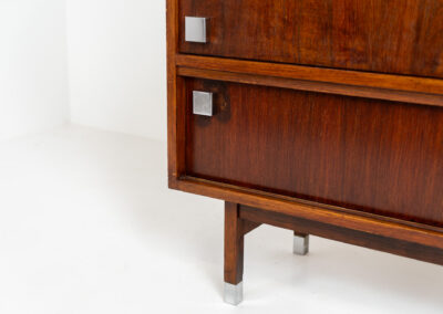 Belgian modernist bar cabinet in rosewood, 1960s. It features a minimalistic design with sleek lines and chrome details. It contains two big and two small sliding doors with lots of storage space on the inside. There are clearly traces of use and age like scratches and some color differences, but overall in good condition. We have a matching sideboard in stock aswell.