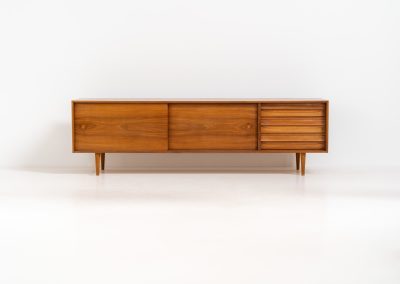 Teak low sideboard from the Platon series by Lothar Wegner (Germany, 1960s). It features two big sliding doors, three drawers and lots of storage space. The combination of the sleek lines and the organic drawers is just amazing. It has subtle round inset handles and a beautiful warm woodgrain. It has some color difference on the top and one of the handles is a little damaged. Otherwise, it is in beautiful condition!