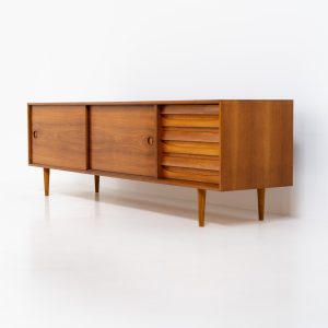 Teak low sideboard from the Platon series by Lothar Wegner (Germany, 1960s). It features two big sliding doors, three drawers and lots of storage space. The combination of the sleek lines and the organic drawers is just amazing. It has subtle round inset handles and a beautiful warm woodgrain. It has some color difference on the top and one of the handles is a little damaged. Otherwise, it is in beautiful condition!