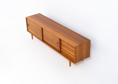 Teak low sideboard from the Platon series by Lothar Wegner (Germany, 1960s). It features two big sliding doors, three drawers and lots of storage space. The combination of the sleek lines and the organic drawers is just amazing. It has subtle round inset handles and a beautiful warm woodgrain. It has some color difference on the top and one of the handles is a little damaged. Otherwise, it is in beautiful condition!