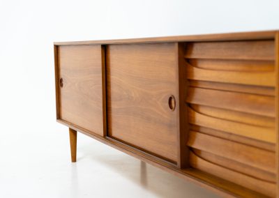 Teak low sideboard from the Platon series by Lothar Wegner (Germany, 1960s). It features two big sliding doors, three drawers and lots of storage space. The combination of the sleek lines and the organic drawers is just amazing. It has subtle round inset handles and a beautiful warm woodgrain. It has some color difference on the top and one of the handles is a little damaged. Otherwise, it is in beautiful condition!