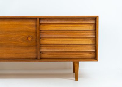 Teak low sideboard from the Platon series by Lothar Wegner (Germany, 1960s). It features two big sliding doors, three drawers and lots of storage space. The combination of the sleek lines and the organic drawers is just amazing. It has subtle round inset handles and a beautiful warm woodgrain. It has some color difference on the top and one of the handles is a little damaged. Otherwise, it is in beautiful condition!