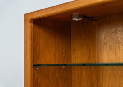 Teak showcase by Svend Dyrlund (Denmark, 1960s). A nice piece with organic shapes and four glass shelves. It has two functional lights on the inside. It is in very good condition.
