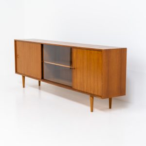 Teak sideboard by Lothar Wegner (Germany, 1960s). It features a teak sliding door, a glass sliding door and a smaller door with a lock and shelves on the inside. A sleek and stylish piece, presented in very good condition.