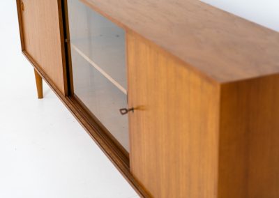 Teak sideboard by Lothar Wegner (Germany, 1960s). It features a teak sliding door, a glass sliding door and a smaller door with a lock and shelves on the inside. A sleek and stylish piece, presented in very good condition.