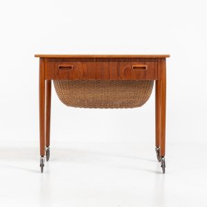 Teak sewing box side table on castors (Denmark, 1960s). This little beauty features a drawer and a wicker basket that can be slid out from both sides. It’s in good condition with some small repair marks.