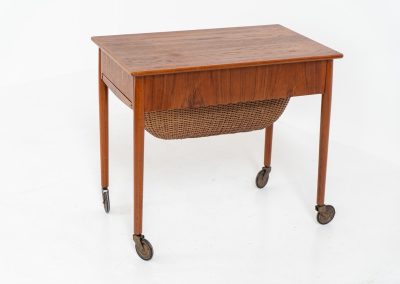 Teak sewing box side table on castors (Denmark, 1960s). This little beauty features a drawer and a wicker basket that can be slid out from both sides. It’s in good condition with some small repair marks.