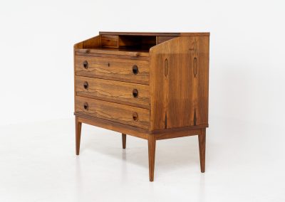 Rosewood secretary by Borge Hansen for Riis Antonsen (Denmark, 1950s). A very elegant piece containing three main drawers, two small drawers and a convenient pull-out leaf. It has very nice details and a mesmerizing woodgrain. The secretary is in very good condition with a few using traces related to its age. Marked by maker. Original key included.