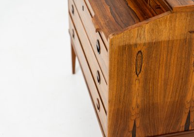 Rosewood secretary by Borge Hansen for Riis Antonsen (Denmark, 1950s). A very elegant piece containing three main drawers, two small drawers and a convenient pull-out leaf. It has very nice details and a mesmerizing woodgrain. The secretary is in very good condition with a few using traces related to its age. Marked by maker. Original key included.