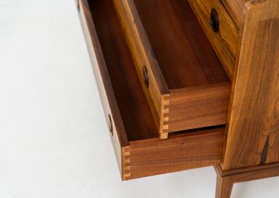 Rosewood secretary by Borge Hansen for Riis Antonsen (Denmark, 1950s). A very elegant piece containing three main drawers, two small drawers and a convenient pull-out leaf. It has very nice details and a mesmerizing woodgrain. The secretary is in very good condition with a few using traces related to its age. Marked by maker. Original key included.