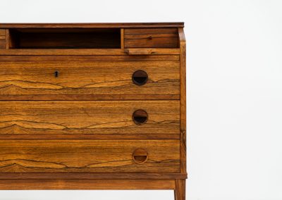 Rosewood secretary by Borge Hansen for Riis Antonsen (Denmark, 1950s). A very elegant piece containing three main drawers, two small drawers and a convenient pull-out leaf. It has very nice details and a mesmerizing woodgrain. The secretary is in very good condition with a few using traces related to its age. Marked by maker. Original key included.