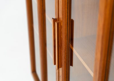 Teak showcase by Ib Kofod-Larsen for Faarup Møbelfabrik (Denmark, 1960s). This beautiful showcase features a stunning teak woodgrain with intricate details throughout. It has two doors with elegant handles and glass panels, providing a clear view of the interior. Inside, there are three adjustable shelves, offering lots of storage options. It is in perfect condition and labeled by maker.