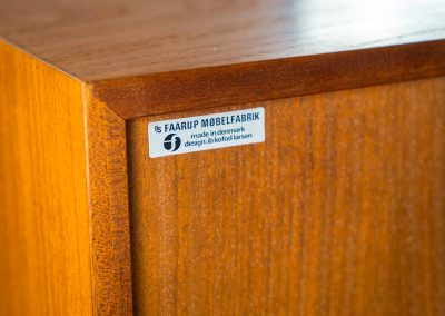 Teak showcase by Ib Kofod-Larsen for Faarup Møbelfabrik (Denmark, 1960s). This beautiful showcase features a stunning teak woodgrain with intricate details throughout. It has two doors with elegant handles and glass panels, providing a clear view of the interior. Inside, there are three adjustable shelves, offering lots of storage options. It is in perfect condition and labeled by maker.