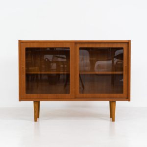 Display cabinet by Poul Hundevad (Denmark, 1960s). A convenient little piece featuring two sliding doors with a glass panel in them, and two adjustable shelves on the inside. In perfect condition and marked by maker.