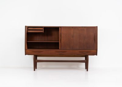 Teak highboard by Jensen & Mølholm (Denmark, 1960s). This stunning piece features two large sliding doors, three drawers, and lots of internal storage with three adjustable shelves and two small drawers. Crafted from warm, natural-looking teak, it showcases beautiful organic curves and elegant bent plywood handles. It is in very good condition with mild age marks and a little color difference on the left panel, as shown on the picture