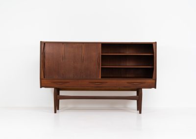 Teak highboard by Jensen & Mølholm (Denmark, 1960s). This stunning piece features two large sliding doors, three drawers, and lots of internal storage with three adjustable shelves and two small drawers. Crafted from warm, natural-looking teak, it showcases beautiful organic curves and elegant bent plywood handles. It is in very good condition with mild age marks and a little color difference on the left panel, as shown on the picture