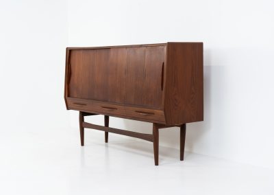 Teak highboard by Jensen & Mølholm (Denmark, 1960s). This stunning piece features two large sliding doors, three drawers, and lots of internal storage with three adjustable shelves and two small drawers. Crafted from warm, natural-looking teak, it showcases beautiful organic curves and elegant bent plywood handles. It is in very good condition with mild age marks and a little color difference on the left panel, as shown on the picture