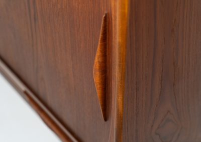 Teak highboard by Jensen & Mølholm (Denmark, 1960s). This stunning piece features two large sliding doors, three drawers, and lots of internal storage with three adjustable shelves and two small drawers. Crafted from warm, natural-looking teak, it showcases beautiful organic curves and elegant bent plywood handles. It is in very good condition with mild age marks and a little color difference on the left panel, as shown on the picture