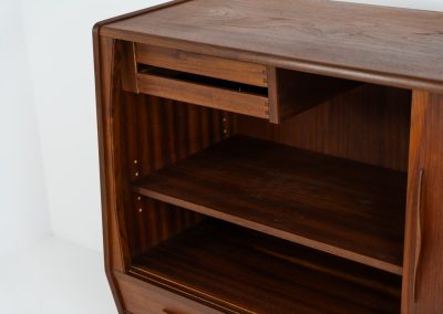 Teak highboard by Jensen & Mølholm (Denmark, 1960s). This stunning piece features two large sliding doors, three drawers, and lots of internal storage with three adjustable shelves and two small drawers. Crafted from warm, natural-looking teak, it showcases beautiful organic curves and elegant bent plywood handles. It is in very good condition with mild age marks and a little color difference on the left panel, as shown on the picture