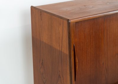 Teak highboard by Jensen & Mølholm (Denmark, 1960s). This stunning piece features two large sliding doors, three drawers, and lots of internal storage with three adjustable shelves and two small drawers. Crafted from warm, natural-looking teak, it showcases beautiful organic curves and elegant bent plywood handles. It is in very good condition with mild age marks and a little color difference on the left panel, as shown on the picture