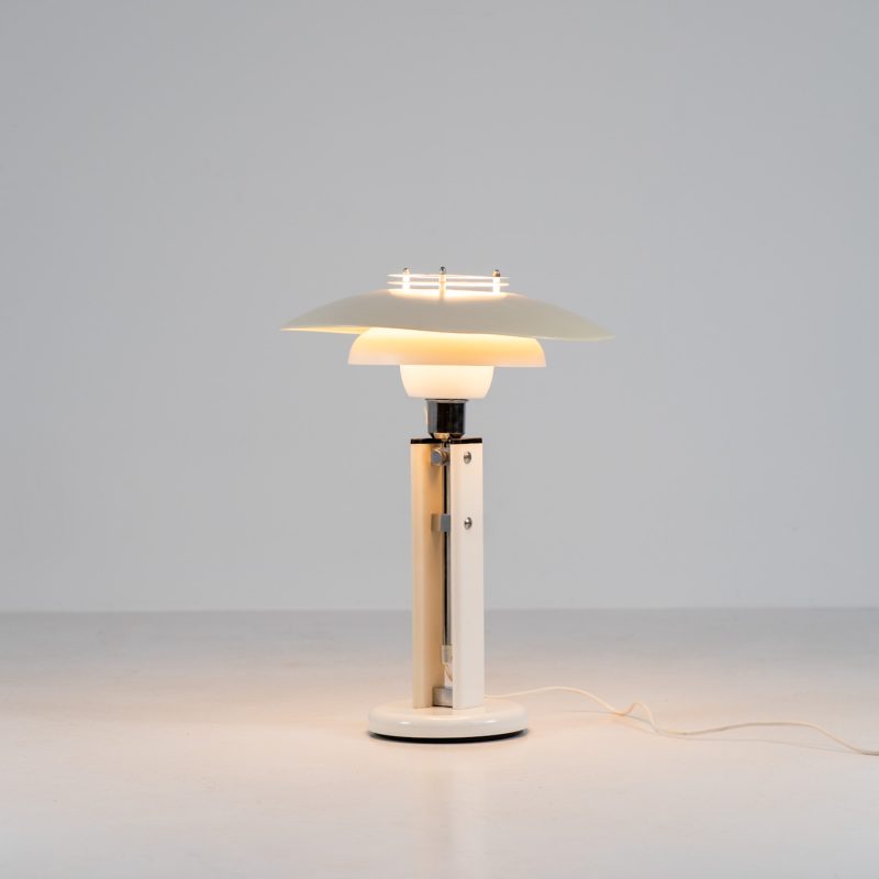 Danish table lamp, 1970s. We don’t know who made this one, but it is clearly inspired by Louis Poulsen’s work. The lamp is easy adjustable in highly with a chrome wheel. It’s made out of white lacquered metal with chrome details. It is in good vintage condition. The shade is not perfectly aligned anymore and the lacquer has some small color differences.