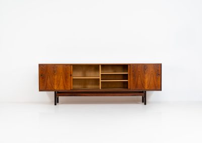 Rare XL sideboard in rosewood by Ib Kofod-Larsen for Faarup (Denmark, 1950s). This piece exudes pure luxury, featuring four large sliding doors with amazing inset handles and lots of storage space with adjustable drawers and shelves inside. The exterior is crafted from rosewood with a glossy finish, showcasing a stunning woodgrain, while the oak-finished interior provides a beautiful contrast. This hard to find piece presents itself in amazing vintage condition with minimal sings of a previous life. The doors slide really smooth. Marked by maker.