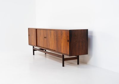 Rare XL sideboard in rosewood by Ib Kofod-Larsen for Faarup (Denmark, 1950s). This piece exudes pure luxury, featuring four large sliding doors with amazing inset handles and lots of storage space with adjustable drawers and shelves inside. The exterior is crafted from rosewood with a glossy finish, showcasing a stunning woodgrain, while the oak-finished interior provides a beautiful contrast. This hard to find piece presents itself in amazing vintage condition with minimal sings of a previous life. The doors slide really smooth. Marked by maker.
