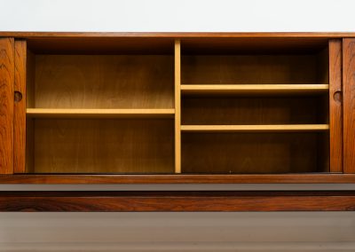 Rare XL sideboard in rosewood by Ib Kofod-Larsen for Faarup (Denmark, 1950s). This piece exudes pure luxury, featuring four large sliding doors with amazing inset handles and lots of storage space with adjustable drawers and shelves inside. The exterior is crafted from rosewood with a glossy finish, showcasing a stunning woodgrain, while the oak-finished interior provides a beautiful contrast. This hard to find piece presents itself in amazing vintage condition with minimal sings of a previous life. The doors slide really smooth. Marked by maker.