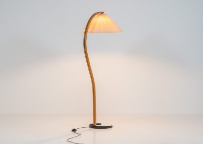 Magnificent Caprani floor lamp by Mads Caprani (Denmark, 1970s). This iconic and hard to find piece features a graceful beech ark, a cast iron base and its original linen pleated shade. The lamp is in original and very good condition, with only minor using traces on the shade, as shown on the pictures. Labeled by maker.