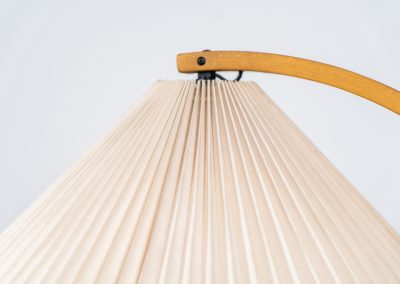 Magnificent Caprani floor lamp by Mads Caprani (Denmark, 1970s). This iconic and hard to find piece features a graceful beech ark, a cast iron base and its original linen pleated shade. The lamp is in original and very good condition, with only minor using traces on the shade, as shown on the pictures. Labeled by maker.