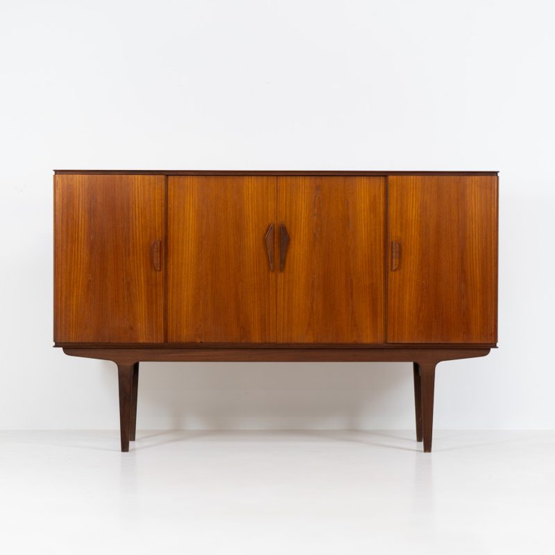 Danish highboard in teak, 1960s. A beautiful mid-century piece crafted in rich teak wood, featuring two spacious doors and two smooth-sliding doors, offering lots of storage and a stylish bar unit inside. The highboard showcases a warm, natural woodgrain, elegant rounded edges, and distinctive handles. It is in very good condition with mild age-related marks.