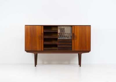 Danish highboard in teak, 1960s. A beautiful mid-century piece crafted in rich teak wood, featuring two spacious doors and two smooth-sliding doors, offering lots of storage and a stylish bar unit inside. The highboard showcases a warm, natural woodgrain, elegant rounded edges, and distinctive handles. It is in very good condition with mild age-related marks.