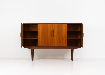 Danish highboard in teak, 1960s. A beautiful mid-century piece crafted in rich teak wood, featuring two spacious doors and two smooth-sliding doors, offering lots of storage and a stylish bar unit inside. The highboard showcases a warm, natural woodgrain, elegant rounded edges, and distinctive handles. It is in very good condition with mild age-related marks.