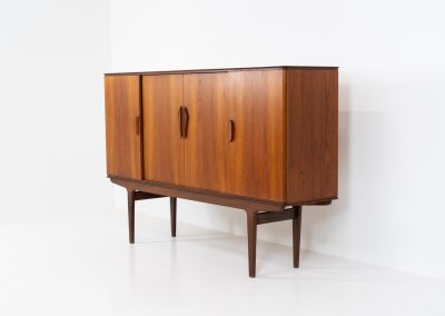 Danish highboard in teak, 1960s. A beautiful mid-century piece crafted in rich teak wood, featuring two spacious doors and two smooth-sliding doors, offering lots of storage and a stylish bar unit inside. The highboard showcases a warm, natural woodgrain, elegant rounded edges, and distinctive handles. It is in very good condition with mild age-related marks.