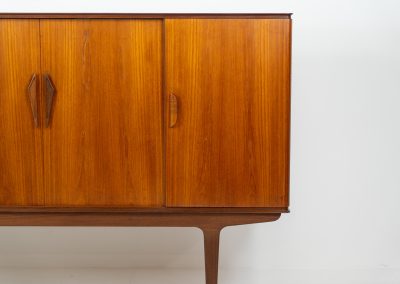 Danish highboard in teak, 1960s. A beautiful mid-century piece crafted in rich teak wood, featuring two spacious doors and two smooth-sliding doors, offering lots of storage and a stylish bar unit inside. The highboard showcases a warm, natural woodgrain, elegant rounded edges, and distinctive handles. It is in very good condition with mild age-related marks.