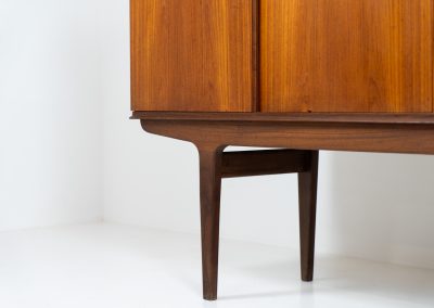 Danish highboard in teak, 1960s. A beautiful mid-century piece crafted in rich teak wood, featuring two spacious doors and two smooth-sliding doors, offering lots of storage and a stylish bar unit inside. The highboard showcases a warm, natural woodgrain, elegant rounded edges, and distinctive handles. It is in very good condition with mild age-related marks.