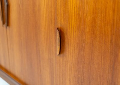 Danish highboard in teak, 1960s. A beautiful mid-century piece crafted in rich teak wood, featuring two spacious doors and two smooth-sliding doors, offering lots of storage and a stylish bar unit inside. The highboard showcases a warm, natural woodgrain, elegant rounded edges, and distinctive handles. It is in very good condition with mild age-related marks.