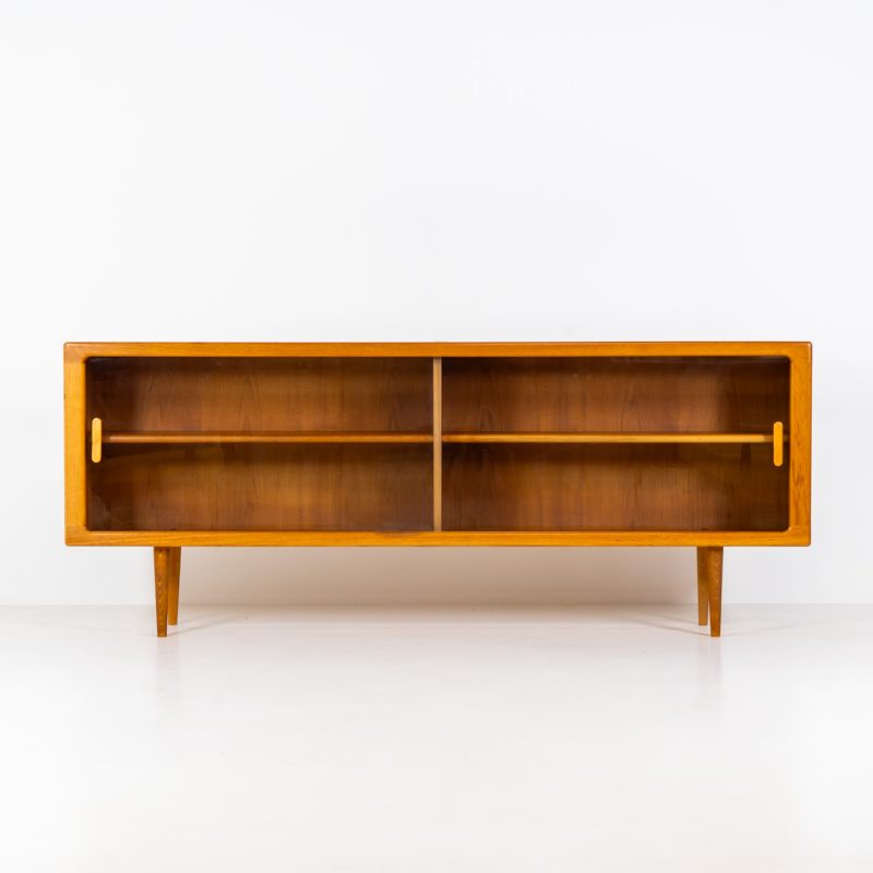 Stunning sideboard with glass doors by CFC Silkeborg (Denmark, 1960s). This elegant mid-century piece, crafted in teak, features beautifully rounded edges, sleek glass sliding doors, and refined wooden handles. Its timeless design combines style with functionality, offering lots of storage space with two adjustable shelves inside. Notably versatile, the sideboard includes three wall mounts on the back, allowing it to be used as a floating sideboard if desired. The legs can be easily removed for this purpose. In very good condition, with only two small repair marks.
