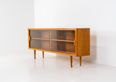 Stunning sideboard with glass doors by CFC Silkeborg (Denmark, 1960s). This elegant mid-century piece, crafted in teak, features beautifully rounded edges, sleek glass sliding doors, and refined wooden handles. Its timeless design combines style with functionality, offering lots of storage space with two adjustable shelves inside. Notably versatile, the sideboard includes three wall mounts on the back, allowing it to be used as a floating sideboard if desired. The legs can be easily removed for this purpose. In very good condition, with only two small repair marks.