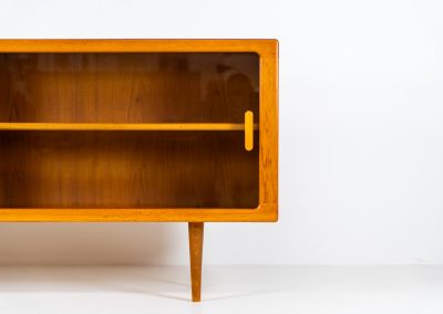 Stunning sideboard with glass doors by CFC Silkeborg (Denmark, 1960s). This elegant mid-century piece, crafted in teak, features beautifully rounded edges, sleek glass sliding doors, and refined wooden handles. Its timeless design combines style with functionality, offering lots of storage space with two adjustable shelves inside. Notably versatile, the sideboard includes three wall mounts on the back, allowing it to be used as a floating sideboard if desired. The legs can be easily removed for this purpose. In very good condition, with only two small repair marks.