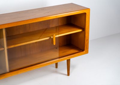 Stunning sideboard with glass doors by CFC Silkeborg (Denmark, 1960s). This elegant mid-century piece, crafted in teak, features beautifully rounded edges, sleek glass sliding doors, and refined wooden handles. Its timeless design combines style with functionality, offering lots of storage space with two adjustable shelves inside. Notably versatile, the sideboard includes three wall mounts on the back, allowing it to be used as a floating sideboard if desired. The legs can be easily removed for this purpose. In very good condition, with only two small repair marks.