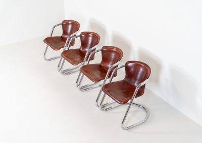 Set of 4 rare leather dining chairs by Willy Rizzo for Metaform (the Netherlands, 1970s). Designed in Italy and manufactured in the Netherlands, these hard to find chairs are a testament to Willy Rizzo’s iconic style. They feature chrome tubular frames and cognac leather seats. The leather showcases a rich patina with visible signs of use, adding character and charm to these remarkable pieces.