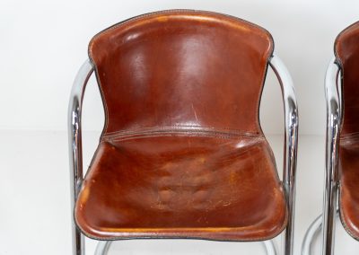 Set of 4 rare leather dining chairs by Willy Rizzo for Metaform (the Netherlands, 1970s). Designed in Italy and manufactured in the Netherlands, these hard to find chairs are a testament to Willy Rizzo’s iconic style. They feature chrome tubular frames and cognac leather seats. The leather showcases a rich patina with visible signs of use, adding character and charm to these remarkable pieces.