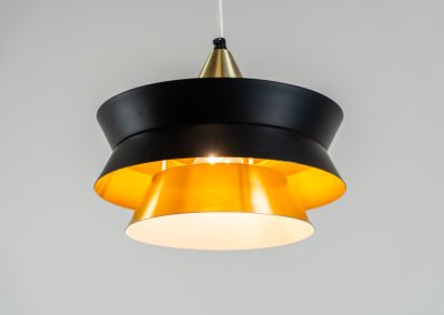 Beautiful messing pendant light by Carl Thore for Granhaga (Sweden, 1960s). This striking mid-century lamp showcases a sophisticated blend of geometric lines and warm metallic tones. Its layered design, combining matte black and brass with a subtle orange interior, creates a stunning interplay of light and shadow. The lamp is rewired and remains in excellent condition.