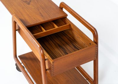 Teak serving trolley by Sikka Møbler (Denmark, 1960s). An elegant and versatile piece crafted from warm teak. It features clean lines, dovetail joinery, and a functional two-tier design with a convenient drawer for storage. The trolley is mounted on smooth-rolling casters, making it both stylish and practical for serving or displaying items. The trolley remains in mint condition.