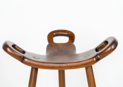 Set of 3 Brutalist “Marbella” stools manufactured by Conoform and attributed to Sergio Rodrigues (Spain, 1970s). This iconic set of Marbella stools, also known as the “Spanish Stool,” exemplifies brutalist design with a sculptural flair. Crafted from solid beech wood, the stools feature a distinctive curved seat and are complemented by a sturdy iron footrest. The set is in good vintage condition, displaying some signs of use such as seat marks and wear consistent with age.