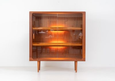 Stunning showcase by Svend Dyrlund (Denmark, 1960s). This exceptional piece features elegant glass doors with beautifully crafted wooden handles, two adjustable shelves, and convenient backlights behind each shelf to highlight your displayed items. Made from rich teak with a natural woodgrain, it perfectly combines functionality with the timeless characteristic of Danish modern design. In splendid condition.