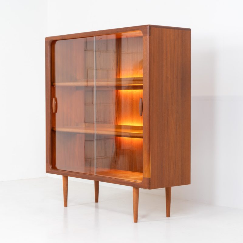 Stunning showcase by Svend Dyrlund (Denmark, 1960s). This exceptional piece features elegant glass doors with beautifully crafted wooden handles, two adjustable shelves, and convenient backlights behind each shelf to highlight your displayed items. Made from rich teak with a natural woodgrain, it perfectly combines functionality with the timeless characteristic of Danish modern design. In splendid condition.