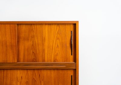 Danish highboard in teak, 1960s. A beautiful mid-century piece crafted in rich teak and standing on oak base, featuring lots of storage space and contrasting black handels. The highboard showcases a warm, natural woodgrain, sleek lines, and distinctive handles. It is in excellent condition with some minor using traces on the top.